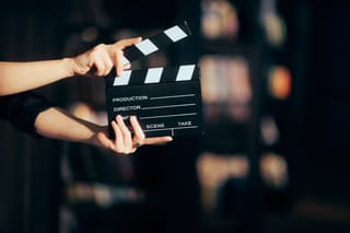 A person holding a movie clapper board in their hands.