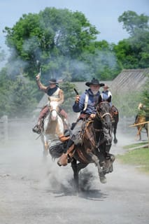 A group of people riding horses down the road.