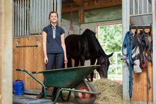 A woman standing next to a cow in a barn.